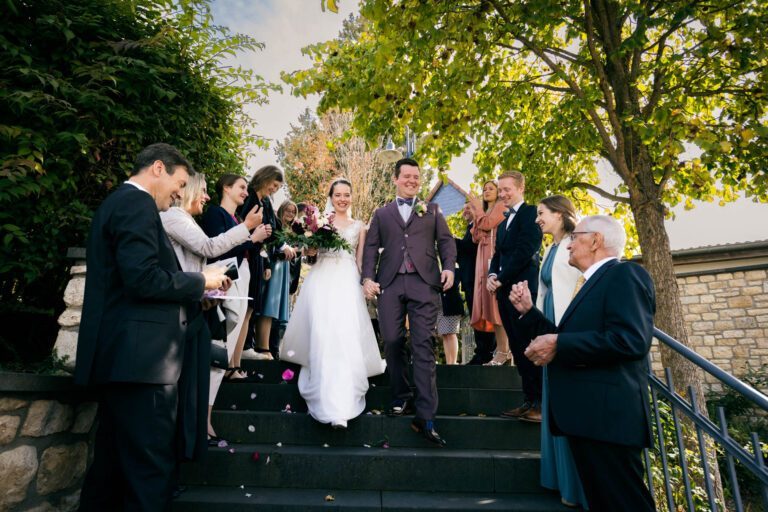 Braut und Bräutigam verlassen die Kirche und werden von den Gästen bejubelt.