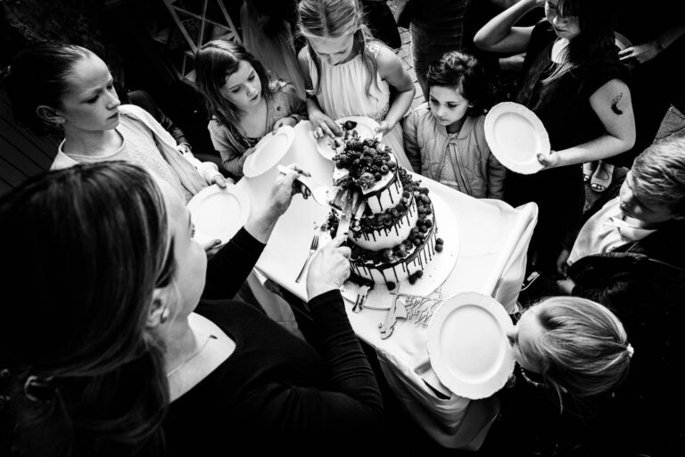 Kinder und Gäste drängeln sich mit ihren Tellern im die Hochzeitstorte.